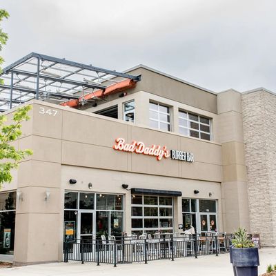 Storefront entrance with fenced sidewalk patio and pyramid heaters under the Bad Daddy's sign