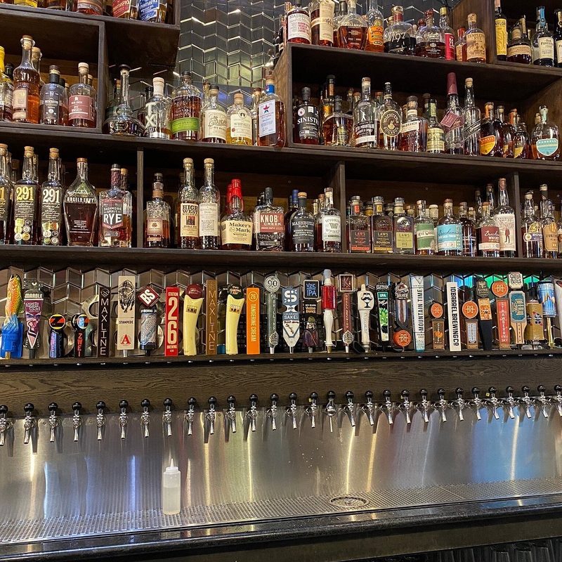 Loveland Tap & Tavern whiskey wall above a row of beer taps along the stainless bar.