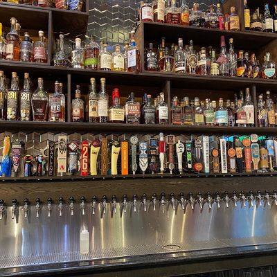 Loveland Tap & Tavern whiskey wall above a row of beer taps along the stainless bar.
