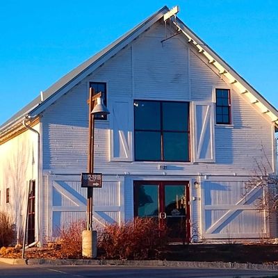 Restored white barn building catching golden-hour light on its peaked roof and double-door entrance.
