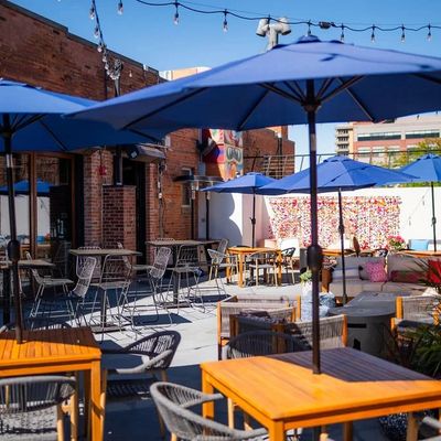 Rooftop with blue umbrellas, wooden tables, and string lights overlooking downtown Fort Collins