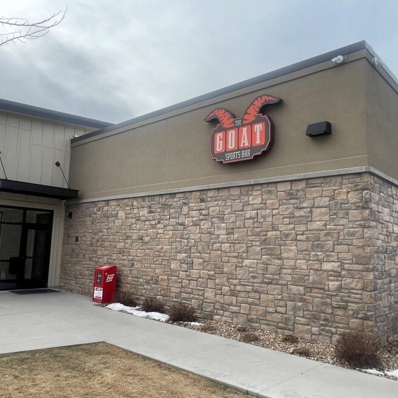 The Goat Sports Bar exterior with horned logo signage above stone-base walls.